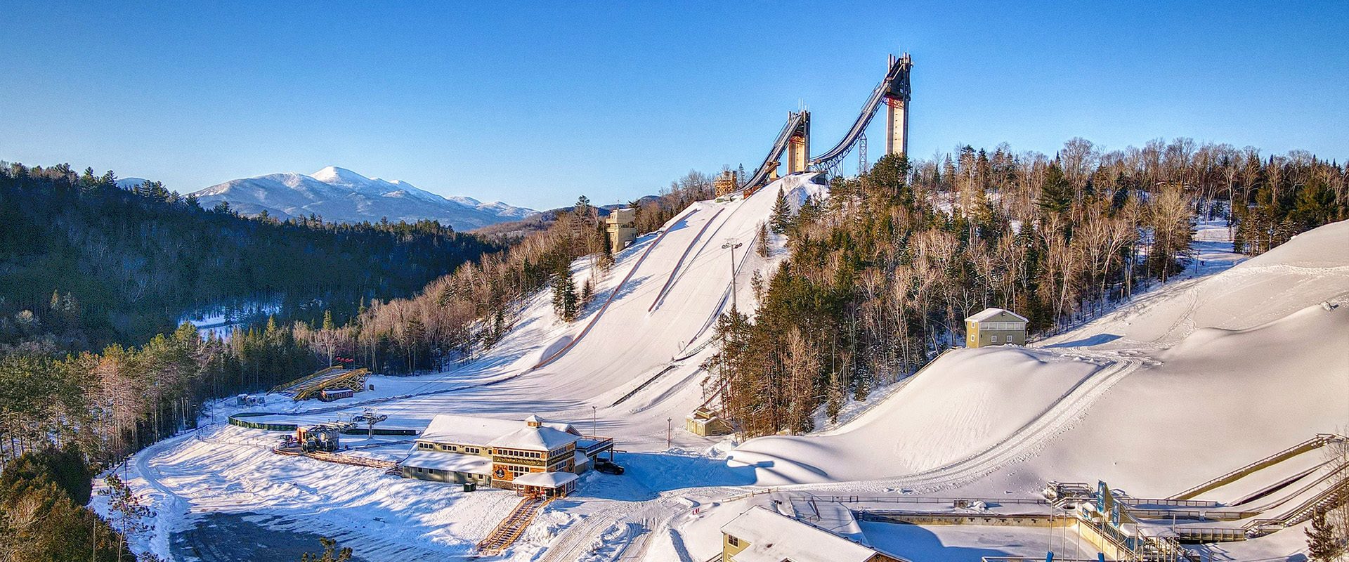 Winter aerial view of the Olympic Jumping Complex showing the ski jumps, aerials jumps, and ausable river.